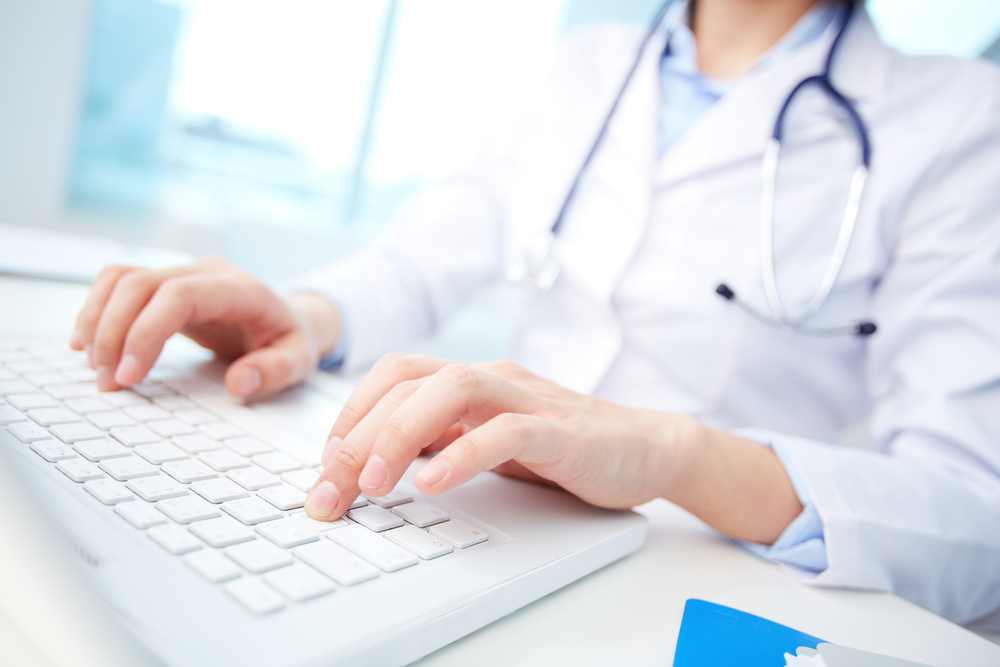 A female doctor providing content marketing for healthcare while typing on a laptop computer.