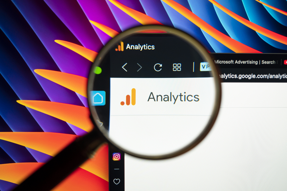 Magnifying glass focusing on the Google Analytics logo, symbolizing tools for tracking website performance and SEO insights